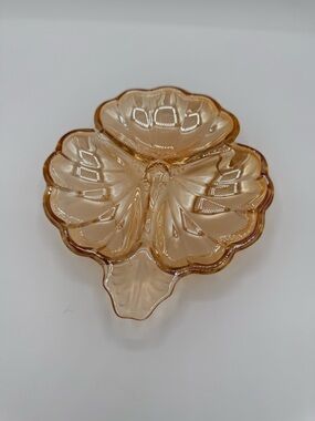 Amber marigold carnival glass three-lobed clover dish with molded patterns.